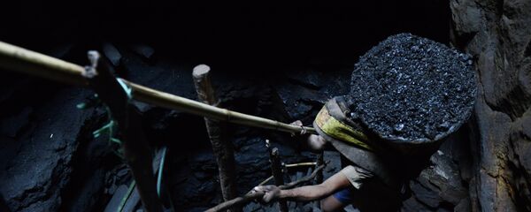 A miner slowly carries a heavy load of wet coal - Sputnik International