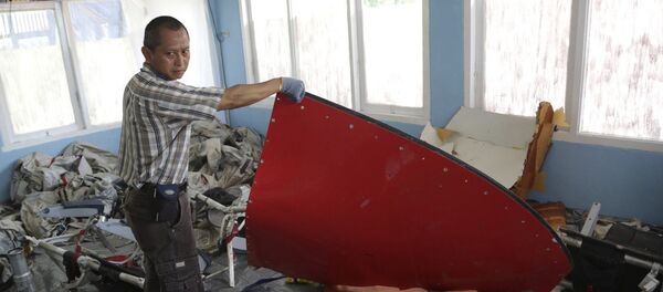 A member of Indonesian Search and Rescue Agency holds a piece which Indonesian Air Force confirmed as from AirAsia Flight 8501, at Disaster Victim Identification room in Pangkalan Bun, Indonesia, Friday, Jan. 9, 2015 A member of Indonesian Search and Rescue Agency holds a piece which Indonesian Air Force confirmed as from AirAsia Flight 8501, at Disaster Victim Identification room in Pangkalan Bun, Indonesia, Friday, Jan. 9, 2015 - Sputnik International