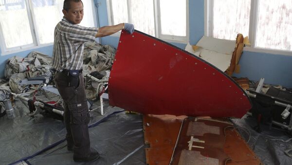 A member of Indonesian Search and Rescue Agency holds a piece which Indonesian Air Force confirmed as from AirAsia Flight 8501, at Disaster Victim Identification room in Pangkalan Bun, Indonesia, Friday, Jan. 9, 2015 - Sputnik International