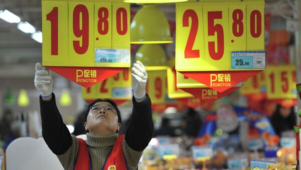 An employee adjusts a price tag at a supermarket in China - Sputnik International