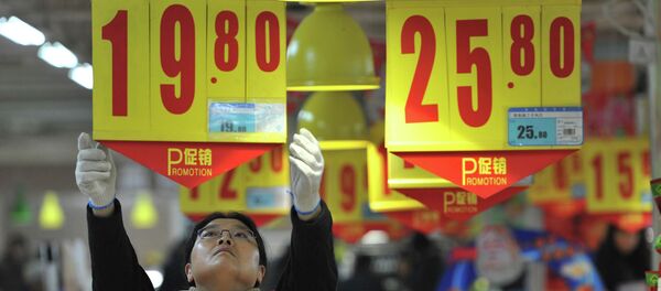 An employee adjusts a price tag at a supermarket in China An employee adjusts a price tag at a supermarket in China - Sputnik International