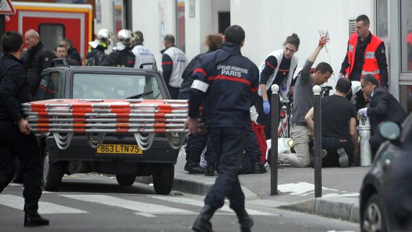 An injured person is treated by nursing staff outside the French satirical newspaper Charlie Hebdo's office, in Paris, Wednesday, Jan. 7, 2015 - Sputnik International