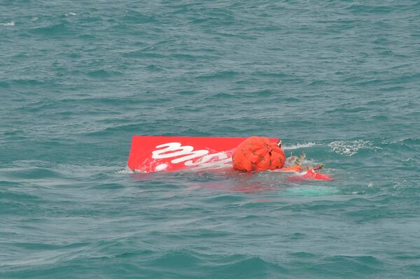 Part of the tail of AirAsia QZ8501 floats on the surface after being lifted as Indonesian navy divers conduct search operations for the black box flight recorders and passengers and crew of the aircraft, in the Java Sea January 10, 2015. - Sputnik International