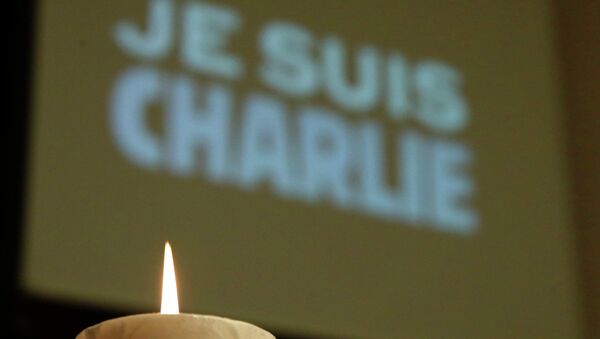 A candle is pictured in front of a Je suis Charlie (I am Charlie) sign - Sputnik International