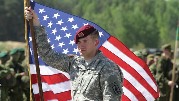 A paratrooper of the 173rd Airborne Brigade of the US Army in Europe holds his country's flag after the final operation of the exercise Black Arrow 2014 in Rukla, Lithuania - Sputnik International