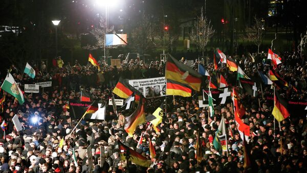 Supporters of anti-immigration movement Patriotic Europeans Against the Islamisation of the West (PEGIDA) hold flags during a demonstration in Dresden - Sputnik International