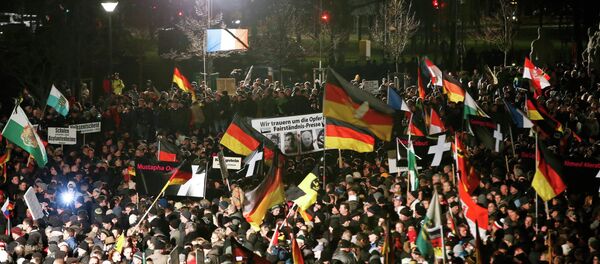 Supporters of anti-immigration movement Patriotic Europeans Against the Islamisation of the West (PEGIDA) hold flags during a demonstration in Dresden Supporters of anti-immigration movement Patriotic Europeans Against the Islamisation of the West (PEGIDA) hold flags during a demonstration in Dresden - Sputnik International