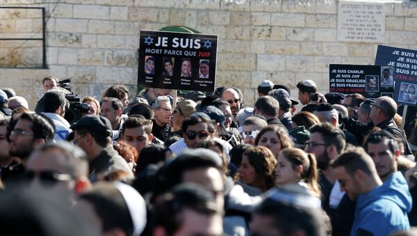 A mourner holds a placard with pictures of the victims of an attack on a Paris grocery on Friday, during their joint funeral in Jerusalem January 13, 2015. - Sputnik International