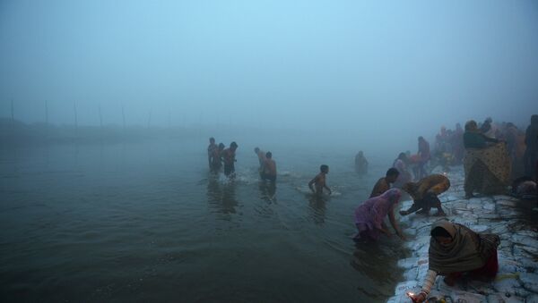 Indian Hindu devotees take a holy dip for the Makar Sankranti festival during the annual Magh Mela gathering at Sangam, the confluence of the rivers Ganges, Yamuna and the mythical Saraswati, during a cold and foggy morning in Allahabad on January 14, 2015 - Sputnik International