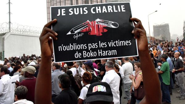 A man holds a placard that reads Je suis Charlie, n'oublions pas les victimes de Boko Haram (I am Charlie, let's not forget the victims of Boko Haram) as people gather outside the French embassy in Abidjan, on January 11, 2015 - Sputnik International