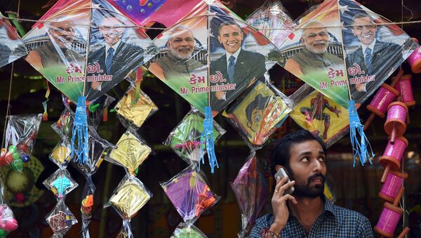 An Indian shopkeeper talks on his mobile phone below kites with images of Indian prime minister Narendra Modi (L) and US President Barack Obama (R) in Mumbai on January 7, 2015 - Sputnik International