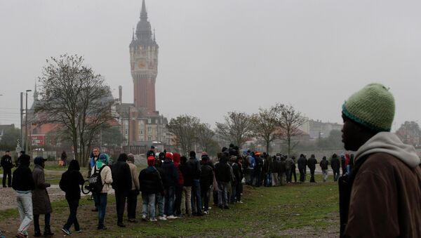 Migrants queue during a daily food distribution close to the city hall in Calais - Sputnik International