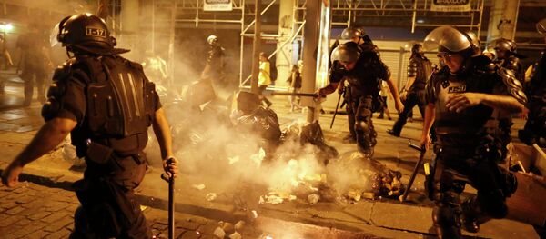 Riot police officers walk past garbage lit on fire by protestors during a demonstration against the increase on bus fares in Rio de Janeiro, Brazil, Friday, Jan. 9, 2015 Riot police officers walk past garbage lit on fire by protestors during a demonstration against the increase on bus fares in Rio de Janeiro, Brazil, Friday, Jan. 9, 2015 - Sputnik International