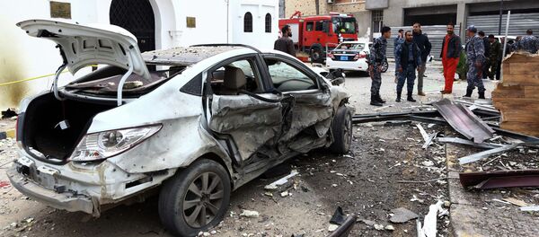 Libyan policemen stand next to a burnt car - Sputnik International