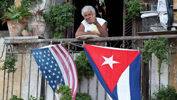 A Cuban gives the thumbs up from his balcony decorated with the US and Cuban flags in Havana - Sputnik International