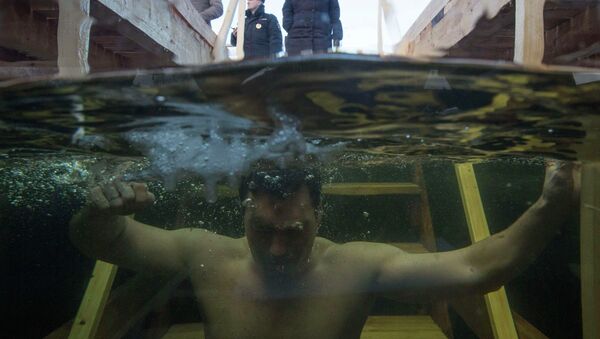 A man immerses himself in an ice hole in the Moskva river during celebrations for Russian Orthodox Epiphany on the outskirts of Moscow - Sputnik International