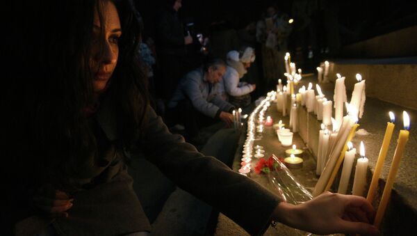 A woman lights a candle in the center of Yerevan on late January 13, 2015 in tribute to the six members of the same family allegedly killed by Russian soldier Valery Permyakov in the Armenian city of Gyumri - Sputnik International