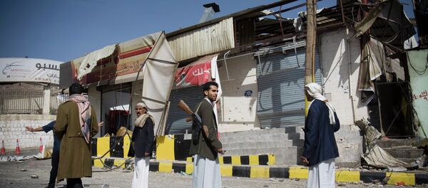 Houthi Shiite Yemeni stand guard in front of a building damaged during recent clashes near the presidential palace in Sanaa, Yemen, Tuesday, Jan. 20, 2015. - Sputnik International