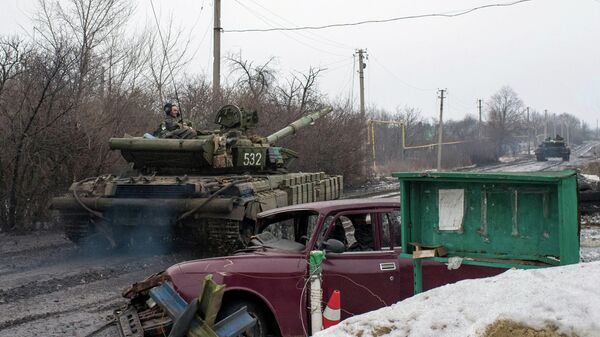 A man rides a Ukrainian tanks past a damaged vehicle in the village of Tonenke, some 5 kilometers from the Donetsk airport - Sputnik International