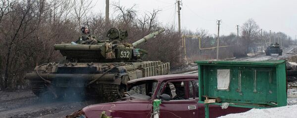 A man rides a Ukrainian tanks past a damaged vehicle in the village of Tonenke, some 5 kilometers from the Donetsk airport A man rides a Ukrainian tanks past a damaged vehicle in the village of Tonenke, some 5 kilometers from the Donetsk airport - Sputnik International
