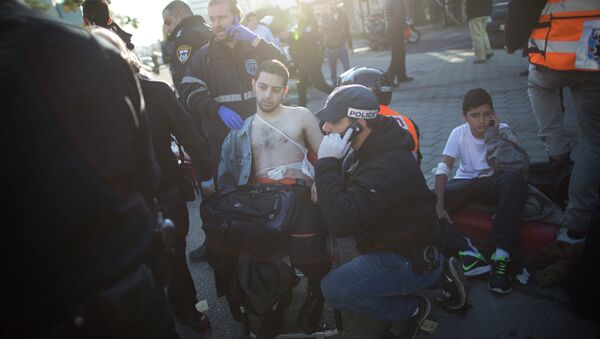 An Israeli police officer and paramedics treat an injured man at the scene of a stabbing in Tel Aviv, Israel - Sputnik International