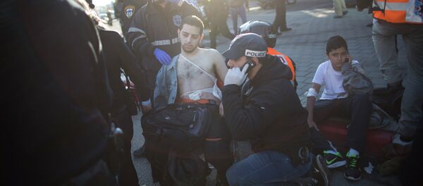 An Israeli police officer and paramedics treat an injured man at the scene of a stabbing in Tel Aviv, Israel - Sputnik International