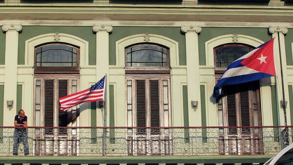 A man stands near the national flags of the U.S. and Cuba (R) on the balcony of a hotel being used by the first U.S. congressional delegation to Cuba since the change of policy announced by U.S. President Barack Obama on December 17, in Havana - Sputnik International