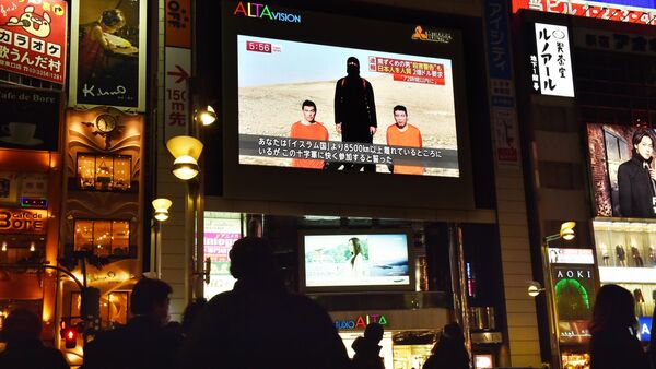 People look at a large TV screen in Tokyo on January 20, 2015 showing news reports about two Japanese men (in orange) who have been kidnapped by the Islamic State group - Sputnik International