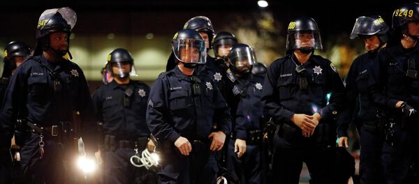 A police officer looks into the crowd, after he was hit on the leg with paint thrown by protesters during an evening demonstration against police violence, in Oakland, California December 13, 2014. A police officer looks into the crowd, after he was hit on the leg with paint thrown by protesters during an evening demonstration against police violence, in Oakland, California December 13, 2014. - Sputnik International