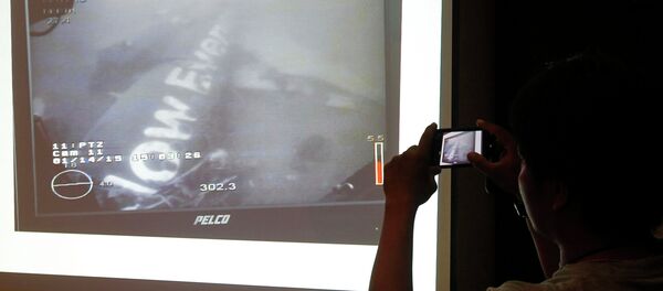 A journalist takes a photograph of an image believed to be of the fuselage of AirAsia Flight QZ8501 A journalist takes a photograph of an image believed to be of the fuselage of AirAsia Flight QZ8501 - Sputnik International