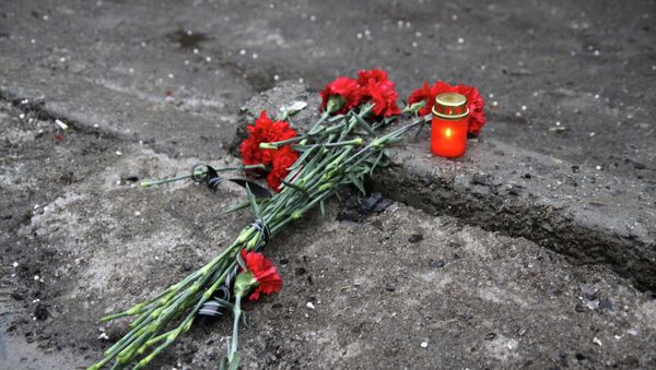 A candle and flowers are layed at a bus stop where 13 people were killed in a trolleybus shelling in Donetsk, eastern Ukraine, on January 22, 2015 - Sputnik International