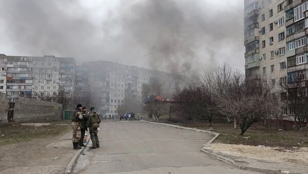 Ukrainian servicemen stand guard on a street near the burning building after a shelling by pro-Russian rebels of a residential sector in Mariupol, eastern Ukraine, January 24, 2015 - Sputnik International