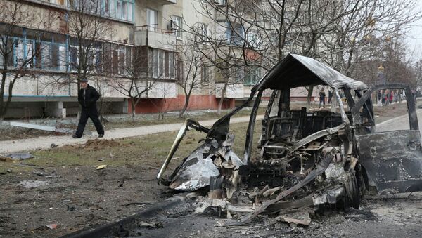 A man walks past a burnt-out vehicle after a shelling  of a residential sector in Mariupol, eastern Ukraine, January 24, 2015 - Sputnik International
