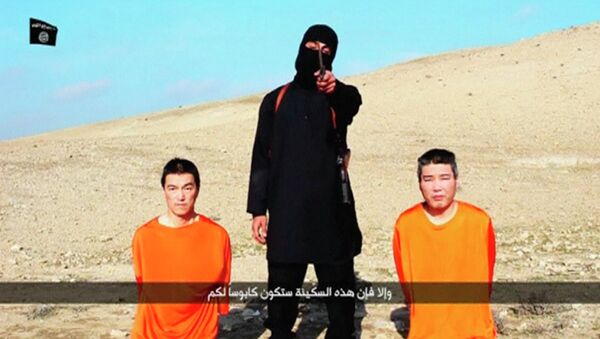 A masked person holding a knife speaks as he stands in between two kneeling men in this still image taken from an online video released by the militant Islamic State group on January 20, 2015 - Sputnik International