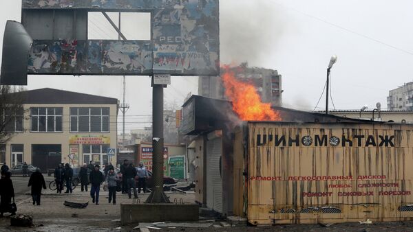 Peole look at a burning shop after shelling in the southern Ukrainian port city of Mariupol on 24, 2015 - Sputnik International