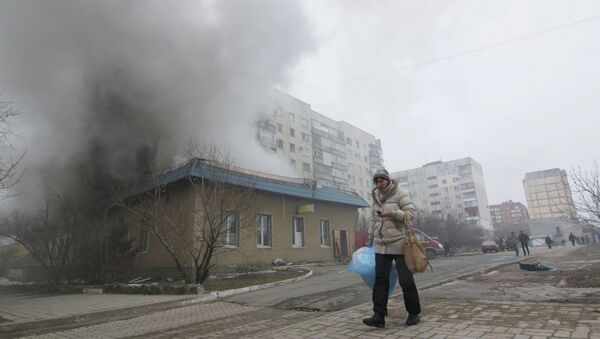 A woman resident passes by a burning house in Mariupol, Ukraine, Saturday, Jan. 24, 2015 - Sputnik International