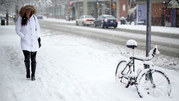 A woman walks past a bicycle covered in snow during a winter snowstorm in Cambridge, Massachusetts January 24, 2015 - Sputnik International