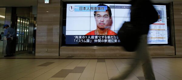 A man walks past screens displaying a television news programme showing an image of Kenji Goto, one of two Japanese citizens taken captive by Islamic State militants, on a street in Tokyo January 25, 2015 A man walks past screens displaying a television news programme showing an image of Kenji Goto, one of two Japanese citizens taken captive by Islamic State militants, on a street in Tokyo January 25, 2015 - Sputnik International