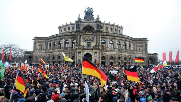 Members of the movement of Patriotic Europeans Against the Islamisation of the West (PEGIDA) hold flags and banners during a PEGIDA demonstration march in Dresden - Sputnik International