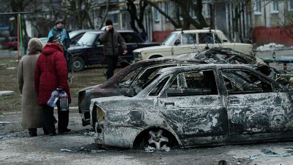 People look at burned out cars as they walk along a street in the southern Ukrainian city of Mariupol - Sputnik International