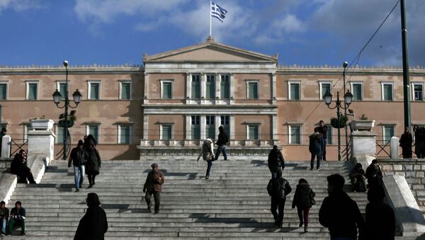 People make their way in central Syntagma Square as the parliament building is pictured in the background in Athens - Sputnik International