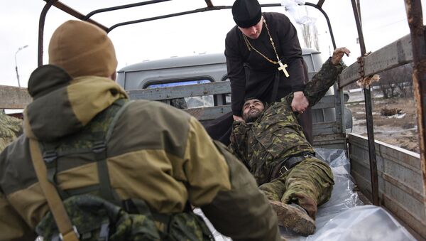 Independent supporters  help a priest to put bodies of killed Ukrainian soldiers in a truck on a check point captured by militia at the town of Krasniy Partizan, eastern Ukraine - Sputnik International