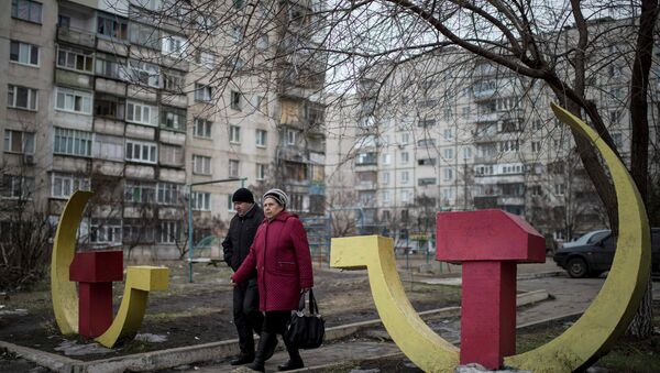 Local residents walk past Soviet-era hammer and sickle sculptures outside an apartment building damaged after Saturday's shellingin Mariupol, Ukraine - Sputnik International