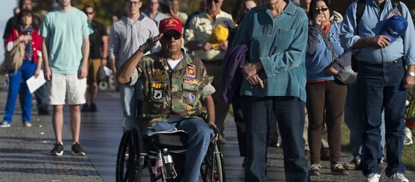 Vietnam War veteran Joe Caballero (C) salutes during the playing of Taps at the Vietnam Veterans Memorial wall on the National Mall in Washington, DC - Sputnik International