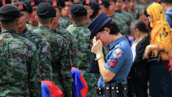 A policewoman wipes her tears as she stands in front of metal caskets containing the bodies of Special Action Force (SAF) police who were killed in Sunday's clash with Muslim rebels, at Villamor Air Base in Pasay city, metro Manila January 29, 2015 - Sputnik International