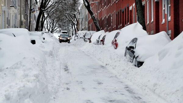 A car makes its way down a street filled with snowed-in vehicles in Boston's Charlestown section, Wednesday, Jan. 28, 2015 one day after a blizzard dumped about two feet of snow in the city - Sputnik International