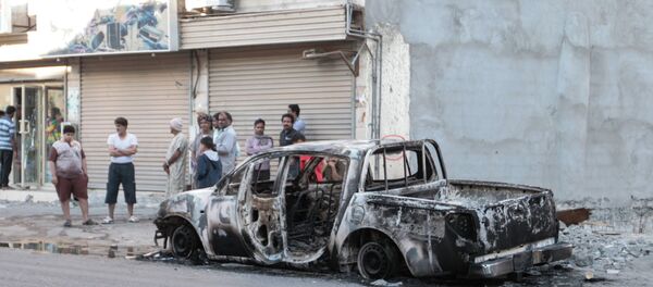 Men stand near a burned vehicle in the eastern town of al-Awamiya, Saudi Arabia Men stand near a burned vehicle in the eastern town of al-Awamiya, Saudi Arabia - Sputnik International