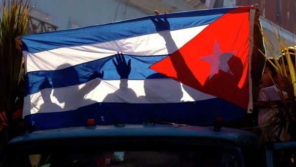 Children's shadows are cast on a Cuban national flag as they take part in a caravan tribute marking the 56th anniversary of the original street party that greeted a triumphant Castro and his rebel army, in Regla, Cuba, Thursday, Jan. 8, 2015 - Sputnik International