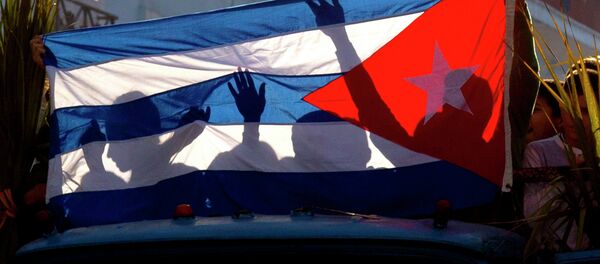 Children's shadows are cast on a Cuban national flag as they take part in a caravan tribute marking the 56th anniversary of the original street party that greeted a triumphant Castro and his rebel army, in Regla, Cuba, Thursday, Jan. 8, 2015 - Sputnik International