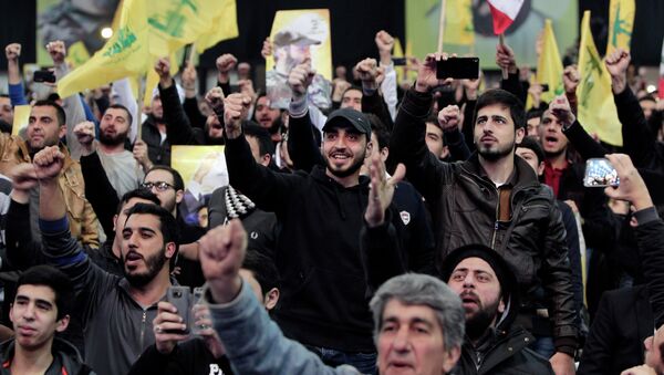 Hezbollah supporters raise their hands in salute as their leader Sheikh Hassan Nasrallah - Sputnik International